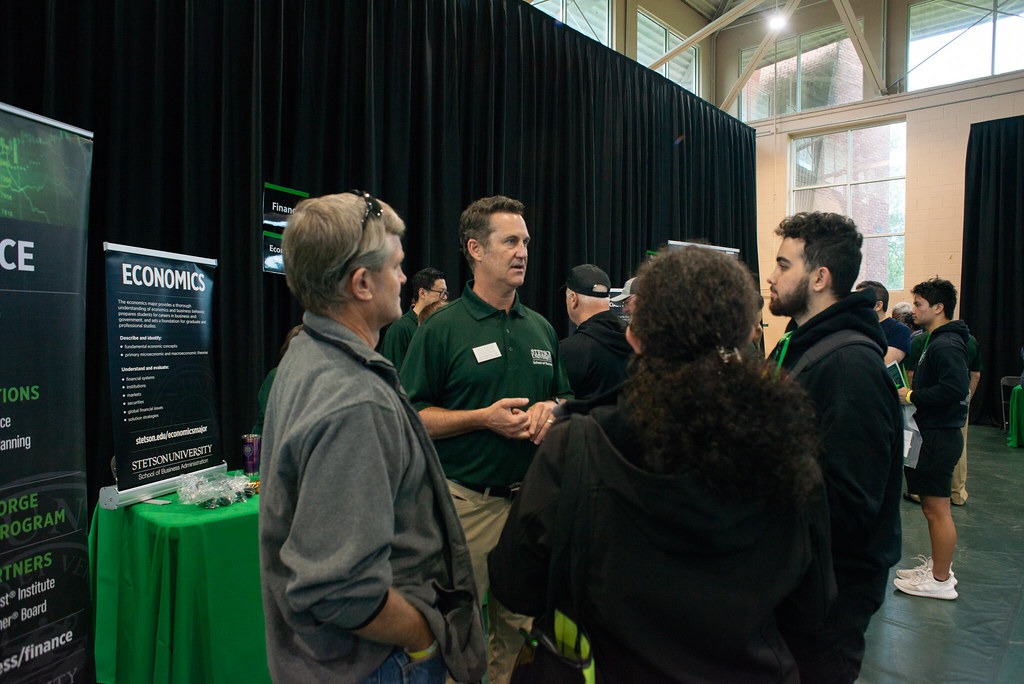 Attendees engage in conversation at an Economics booth during a Stetson University fair.